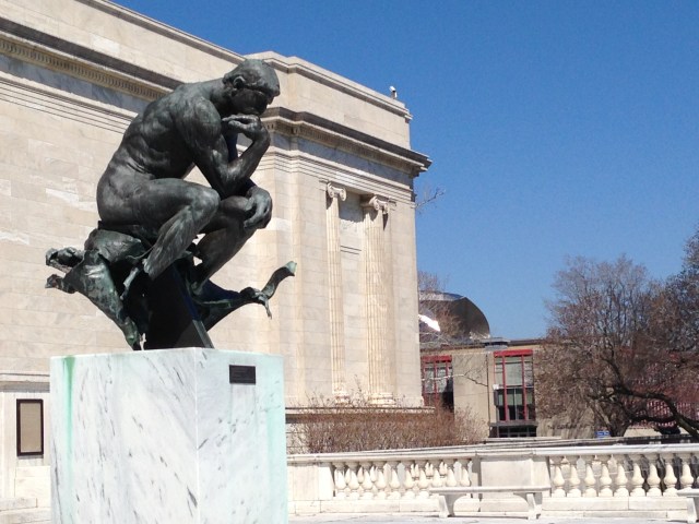 Rodin's The Thinker at front of Museum of Art with Peter B. Lewis Building shining in background.